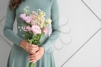 Woman with bouquet of beautiful flowers on light background�