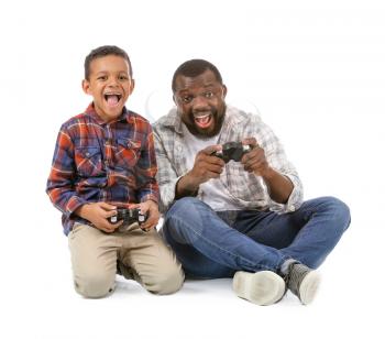Portrait of African-American man and his little son playing video game on white background�