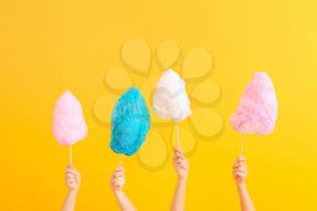 Female hands with different cotton candy on color background�