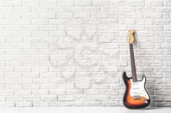 Modern bass guitar near white brick wall�