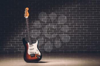 Modern bass guitar against brick wall�