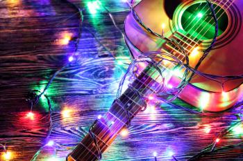 Acoustic guitar with Christmas lights on wooden background�
