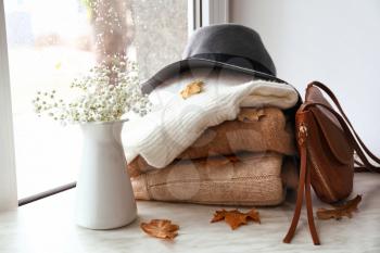 Stack of warm clothes with flowers on window sill�