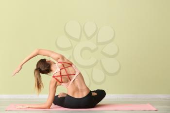 Beautiful young woman practicing yoga indoors�