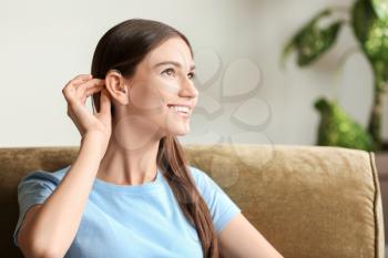 Young woman with hearing aid at home�