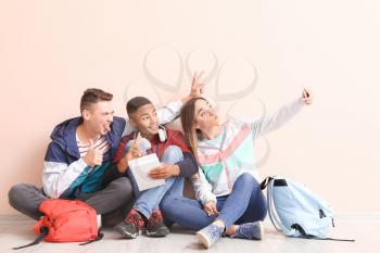 Portrait of teenagers taking selfie near color wall�