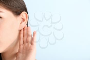 Young woman with hearing problem on color background�