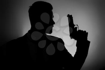Silhouette of male agent with gun on dark background�