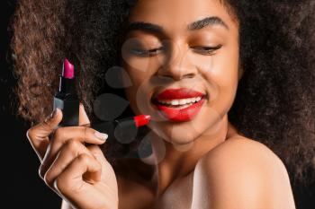 Portrait of beautiful African-American woman with bright lipsticks on dark background, closeup�