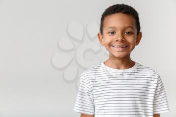 Little African-American boy with hearing aid on light background�