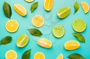 Ripe cut lemons and limes on color background�