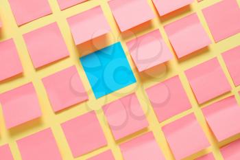 Blue paper sheet among pink ones on color background. Concept of uniqueness�