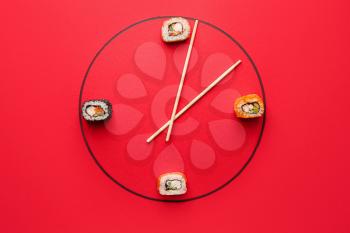Creative clock made of tasty sushi and chopsticks on color background�