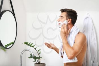 Handsome young man shaving at home�