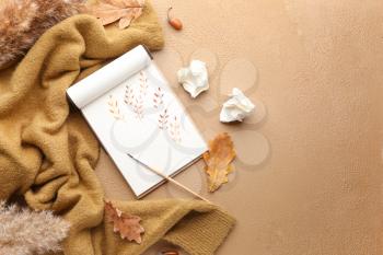 Beautiful autumn composition with sweater, notebook, brush and leaves on color background�