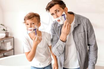 Father and his little son shaving in bathroom�