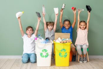Little children and containers with trash near color wall. Concept of recycling�