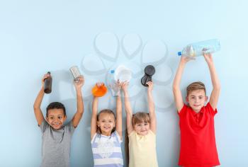Little children with different trash on color background. Concept of recycling�