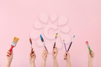 Female hands with painter's supplies on color background�