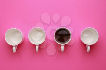 One cup of coffee among empty ones on color background. Concept of uniqueness�
