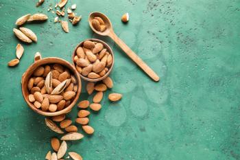 Bowls with tasty almonds on color background�