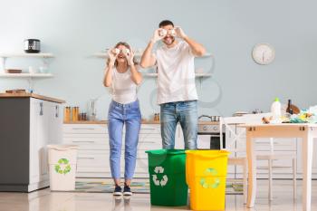 Funny couple sorting garbage at home. Concept of recycling�