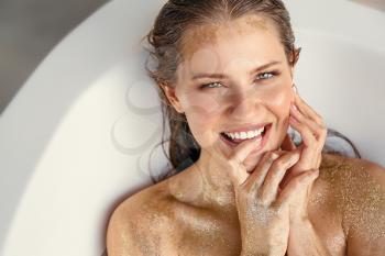 Beautiful young woman with golden glitters on her skin taking bath�