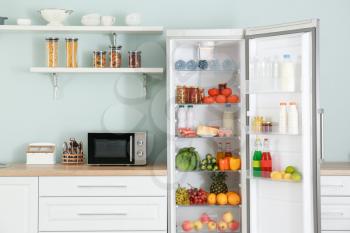 Open big fridge with products in kitchen�