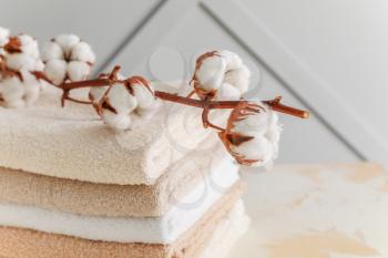 Soft clean towels with cotton flowers on table�