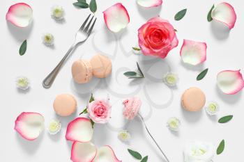 Tasty macarons with rose flowers on white background�