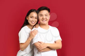 Portrait of happy young Asian couple on color background�