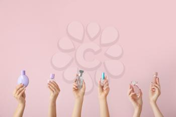 Female hands with different perfume bottles on color background�