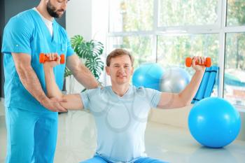 Physiotherapist working with male patient in rehabilitation center�