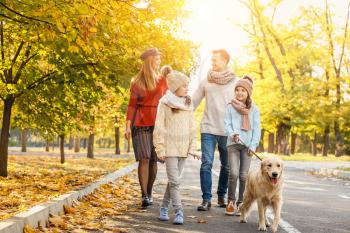 Happy family with dog walking in autumn park�