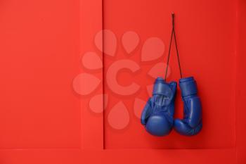 Pair of boxing gloves hanging on color wall�