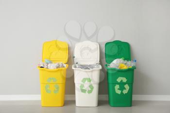 Containers with different types of garbage near light wall. Recycling concept�