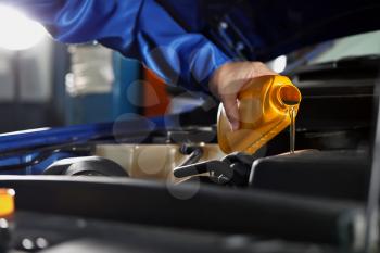 Male mechanic refilling car oil in service center�
