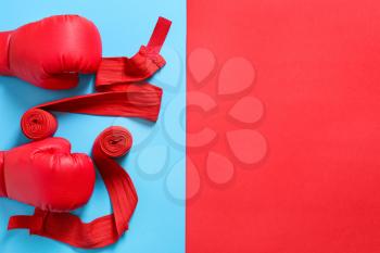 Boxing gloves and wrist bands on color background�