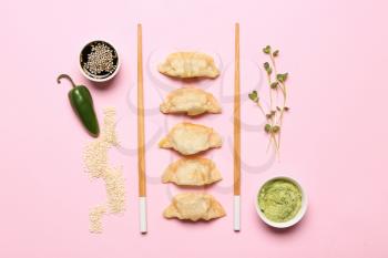 Tasty Japanese gyoza and sauces on color background�