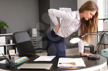 Young businesswoman suffering from back pain in office�