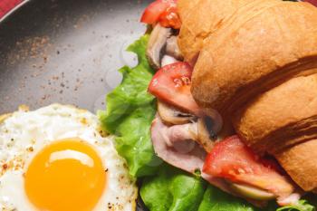 Tasty croissant sandwich with fried egg on plate, closeup�