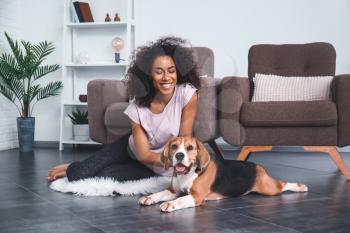 Beautiful African-American woman with cute dog at home�