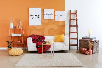 Stylish interior of room with sofa and pumpkins�