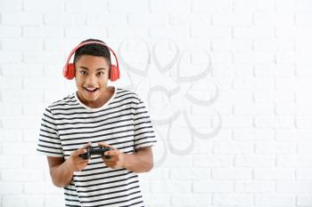 African-American teenager boy with game pad on white brick background�