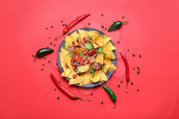 Plate with tasty chili con carne and nachos on color background�