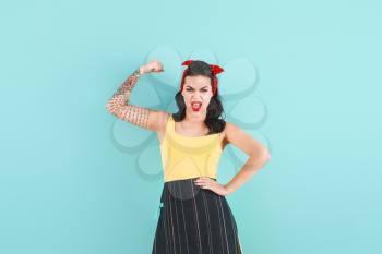 Portrait of strong tattooed pin-up woman on color background�