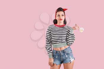 Portrait of beautiful pin-up woman with lollipop on color background�