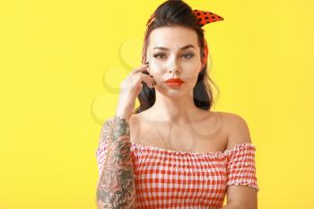 Portrait of beautiful tattooed pin-up woman on color background�