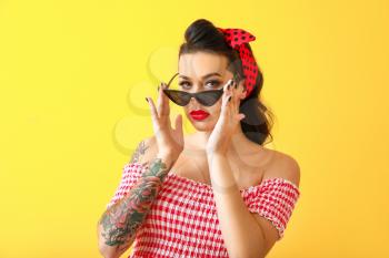 Portrait of beautiful tattooed pin-up woman on color background�
