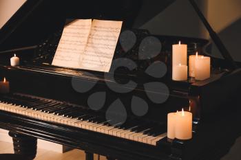 Stylish grand piano with burning candles in evening�